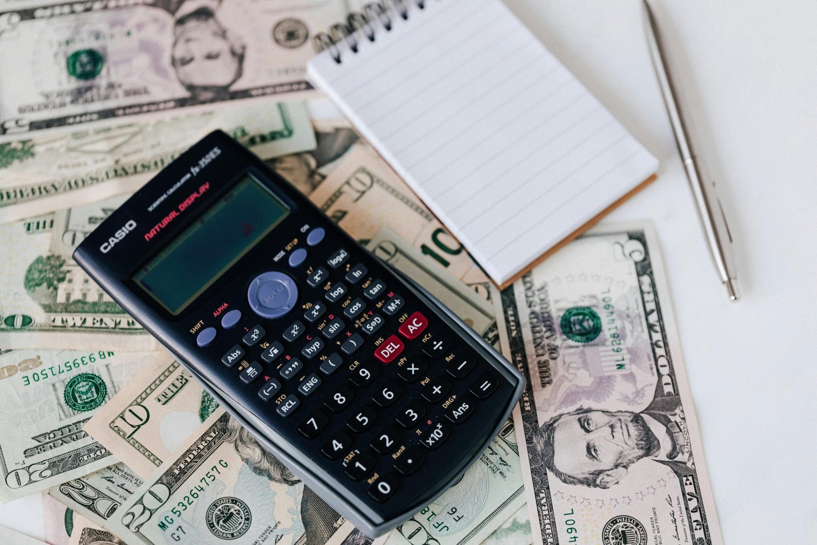 calculator and notepad on a pile of money