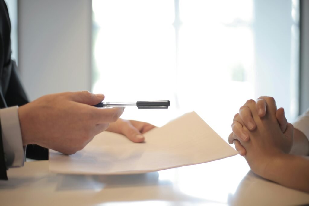 traceloans- a person giving a pen to another person to sign the loan