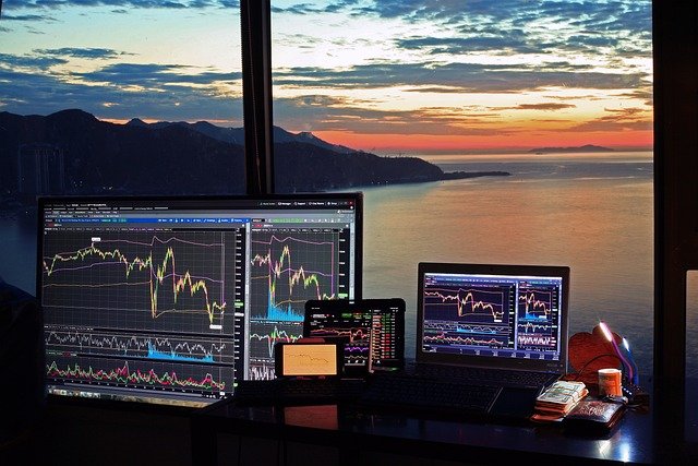 FintechZoom GE Stock: Stock market charts on screens with an ocean sunset view.