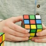 Person solving a 2x2 Rubik's Cube, focusing on techniques to solve it efficiently.