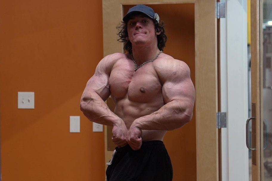 Sam Sulek flexing his muscular physique in a gym setting.