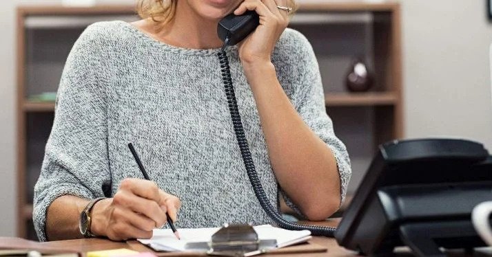 Image of Beverly Greider, Secretary of Director, taking notes while on a phone call, exemplifying her role in managing communication and organization tasks.